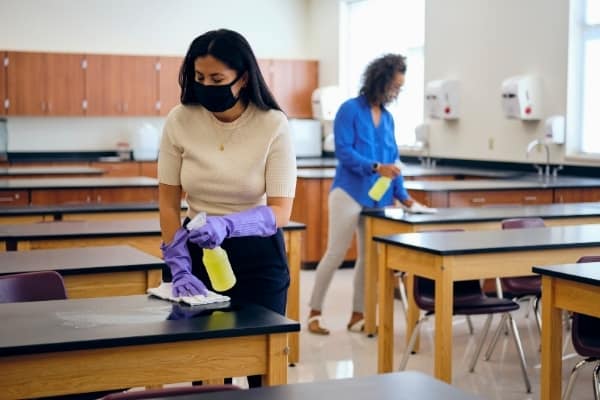 Two ladies cleaning classroom. Education cleaning Cambridge