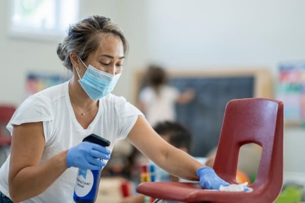 Lady cleans and disinfects classroom in Cambridge.