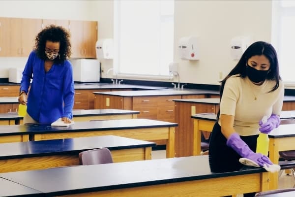 Two ladies disinfecting classroom. Fully managed cleaning service Cambridge