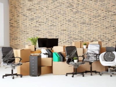 Carton boxes with stuff in empty room. Office move concept. Office clearance service Cambridge.
