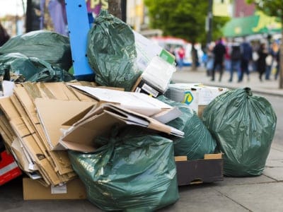 Litter and rubbish bags on the sidewalk of a busy street. Regular waste collections service in Cambridge