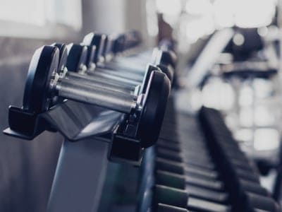 Gym interior background of dumbbells on rack in fitness and workout. Gym cleaning service Cambridge