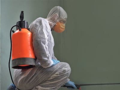 Coronavirus Pandemic. A disinfector in a protective suit and mask sprays disinfectants in the room. Prevention of Coronavirus Disease. Environmental Cleaning and Disinfection with Coronavirus Epidemic. Specialist Cleaning gives a clean office and addresses health and safety Cambridge