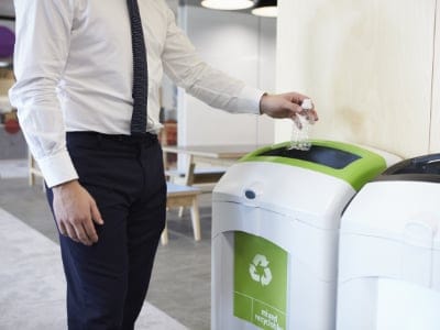 Cleaning services in Cambridge Man in an office throwing plastic bottle into recycling bin. Waste management Cambridge