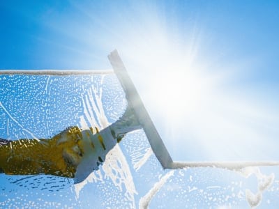 Window cleaners Cambridge office cleaning services window with squeegee and wiper on a sunny day with a bright blue sky. Window cleaning Cambridge